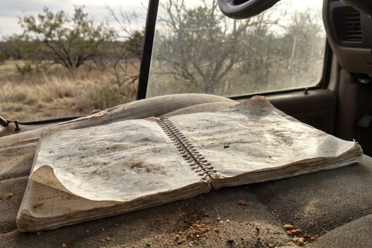 A worn spiral notebook lying open on a dusty truck bench seat